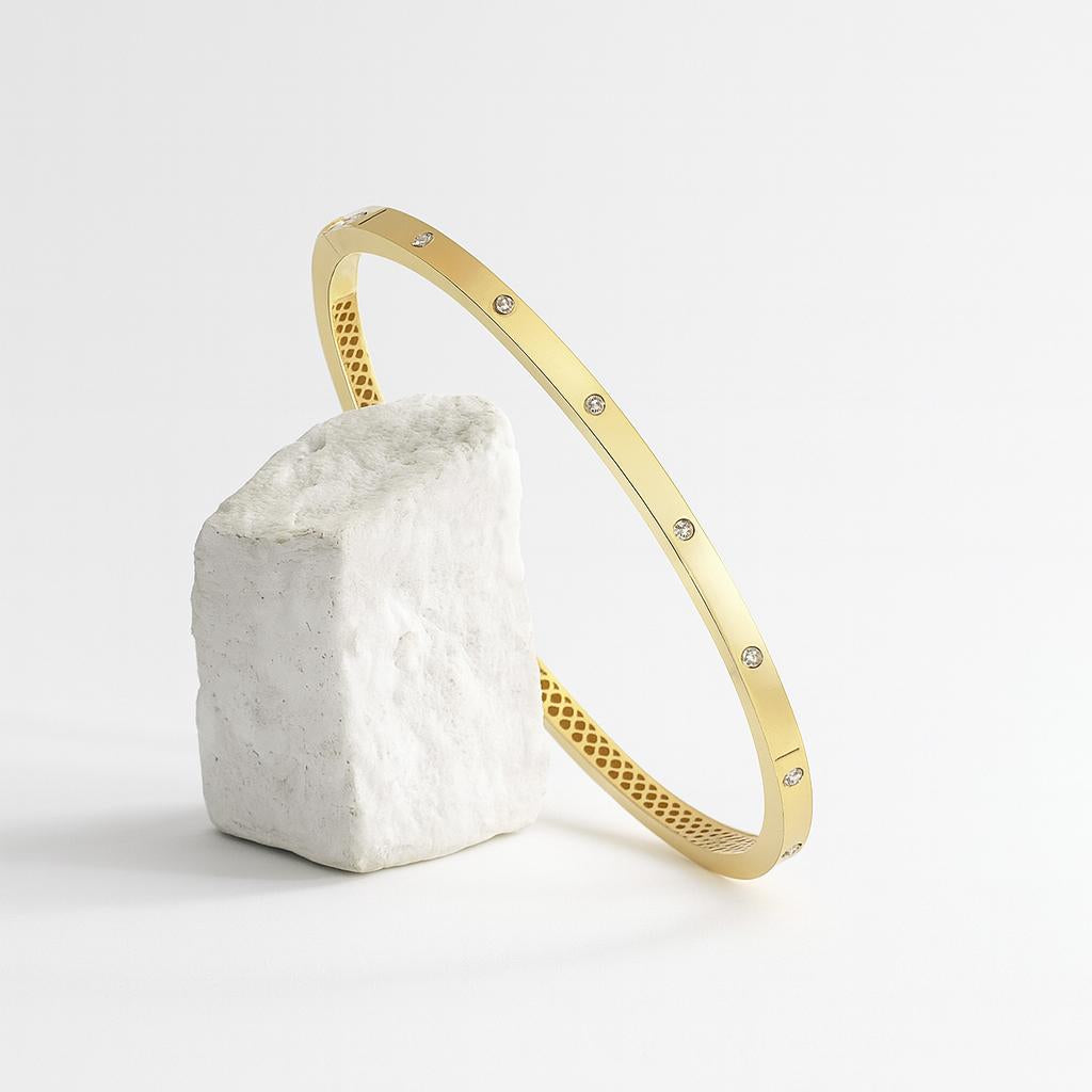 Zlatý náramok CREYO STRUCTURA opretý o biely kameň – umelecký detail